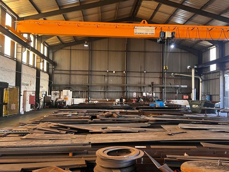 Spacious industrial warehouse featuring a high-capacity overhead gantry crane, steel structural framing, and durable concrete flooring suitable for heavy manufacturing or storage operations.