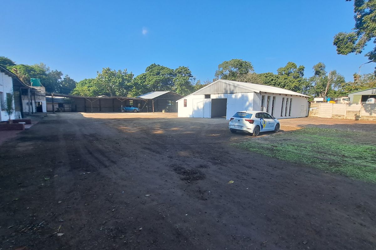 Spacious industrial yard featuring multiple warehouse structures, metal roofing, and a large open concrete area suitable for logistics or storage operations.