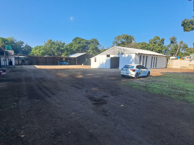 Spacious industrial yard featuring multiple warehouse structures, metal roofing, and a large open concrete area suitable for logistics or storage operations.