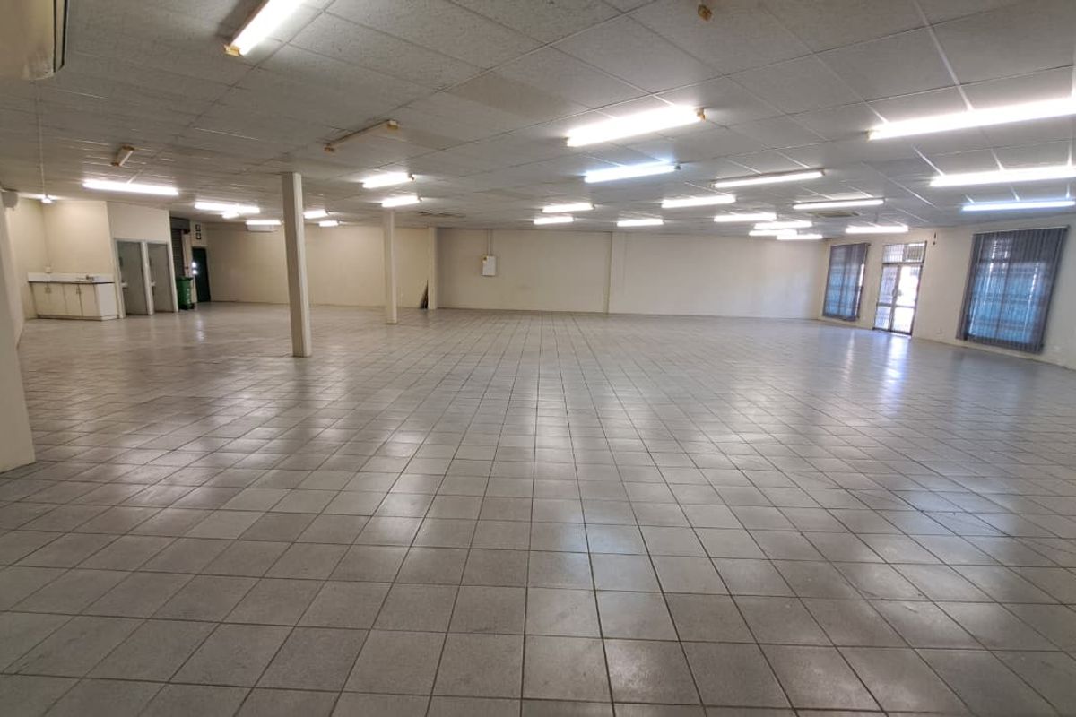 Spacious open-plan retail area featuring tiled flooring, suspended ceilings with fluorescent lighting, and support columns, suitable for various commercial business applications.