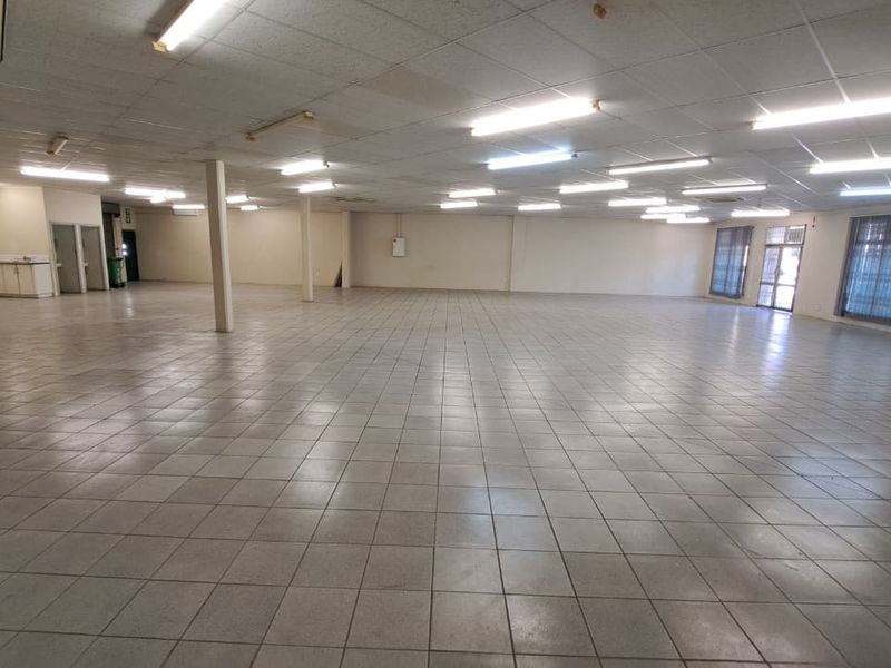 Spacious open-plan retail area featuring tiled flooring, suspended ceilings with fluorescent lighting, and support columns, suitable for various commercial business applications.