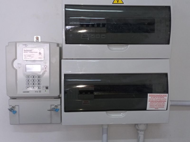 A clean, wall-mounted electrical distribution board and prepaid electricity meter installation in an industrial utility space.