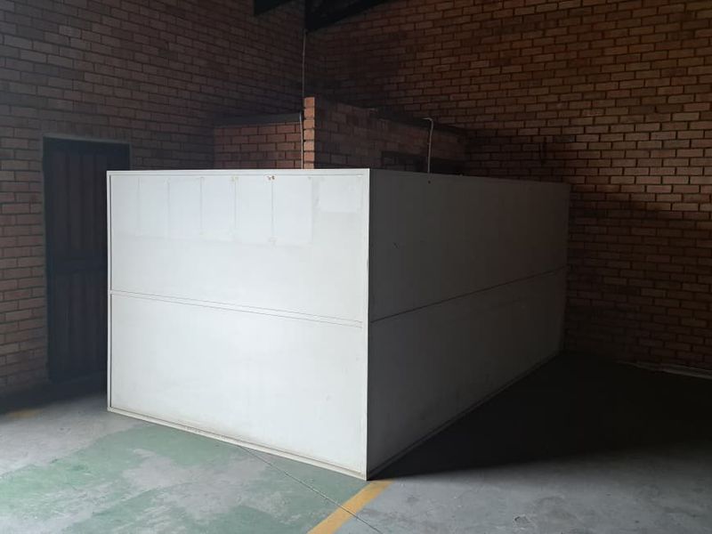 An industrial utility space featuring exposed brick walls, concrete flooring, and a central partition wall, suitable for storage or workshop use.