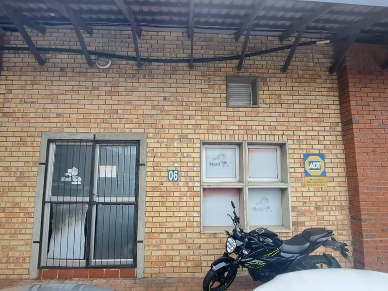 Front facade of an industrial unit featuring face brick construction, security gate, and aluminium window frames with existing signage.