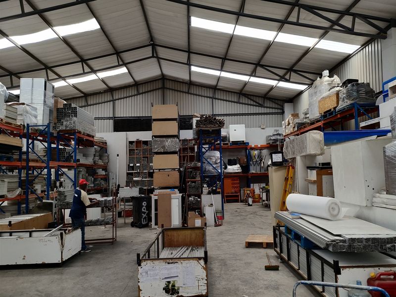 Spacious industrial warehouse featuring high-clearance steel portal frame construction, concrete flooring, integrated skylights, and extensive heavy-duty storage racking systems.
