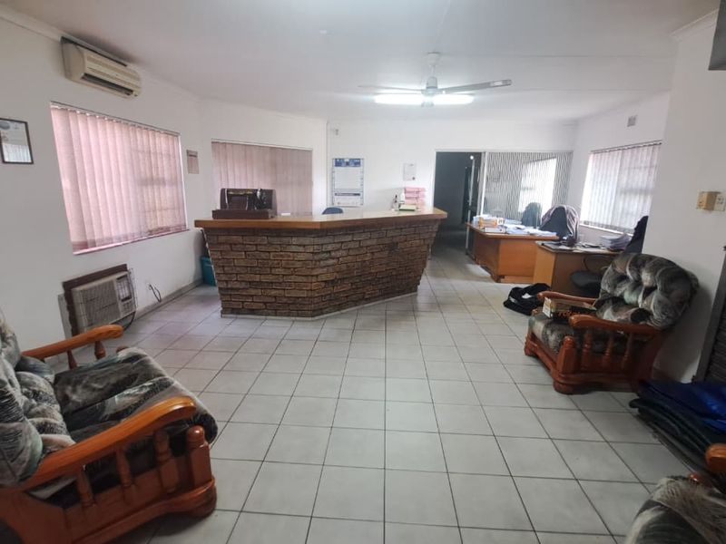 Industrial office space featuring a brick reception counter, ceramic tiled flooring, split system air conditioning, and a secure roller shutter door.