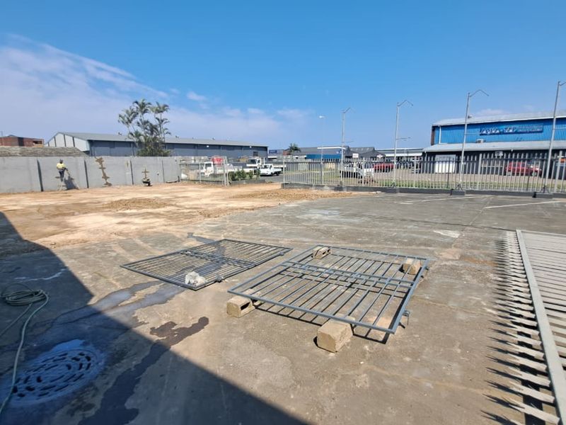 An expansive outdoor concrete yard area featuring perimeter walling and metal security fencing, suitable for industrial or commercial storage use.
