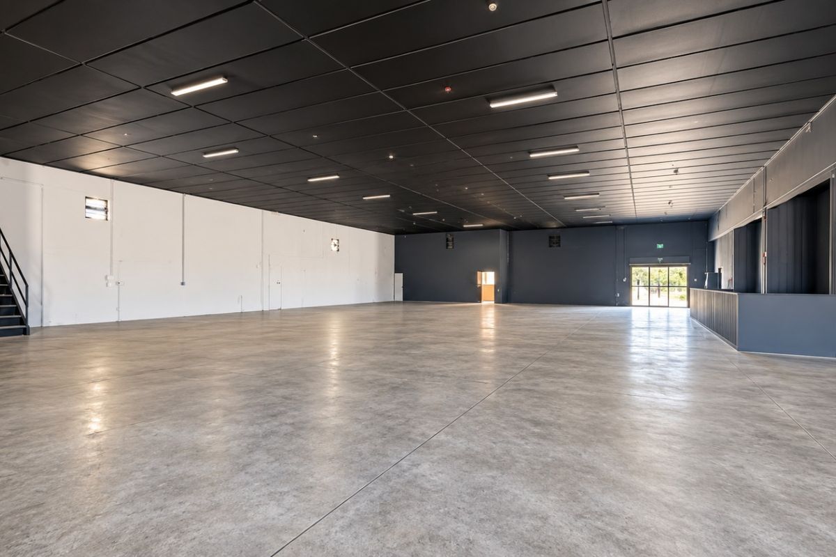 Spacious open-plan retail area featuring polished concrete flooring, a modern dark suspended ceiling with recessed lighting, and a built-in service counter.