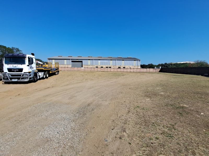 A spacious industrial yard area featuring a perimeter wall and ample open space for vehicle maneuvering or storage.