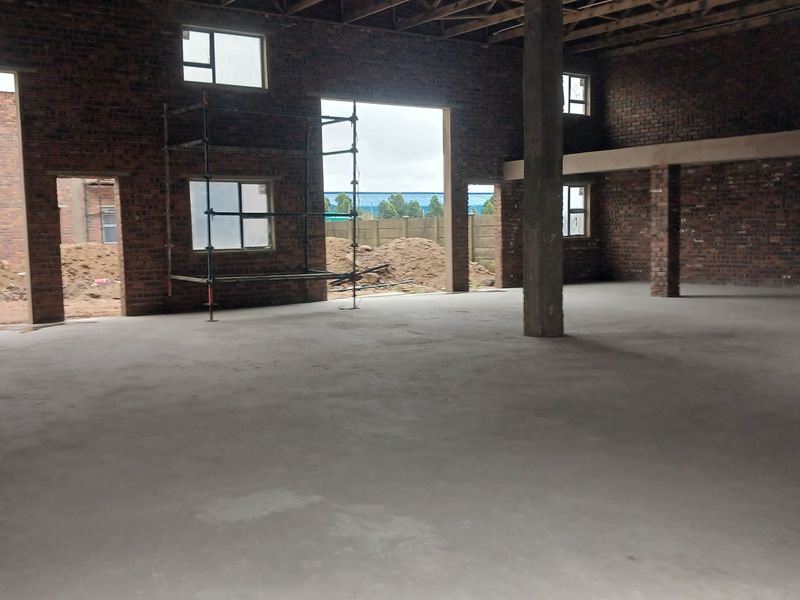 Spacious industrial utility area featuring exposed brick walls, concrete flooring, and high ceilings with exposed timber trusses, currently in an unfinished state.