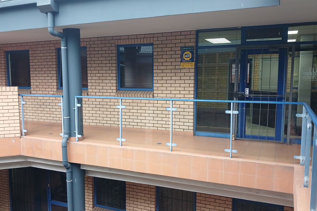 Exterior view of an industrial office building featuring a brick facade, tiled balcony with a glass balustrade, and secure aluminium-framed entrance.