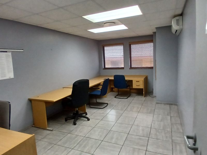 A functional office space featuring tiled flooring, recessed ceiling lighting, an air conditioning unit, and window blinds.
