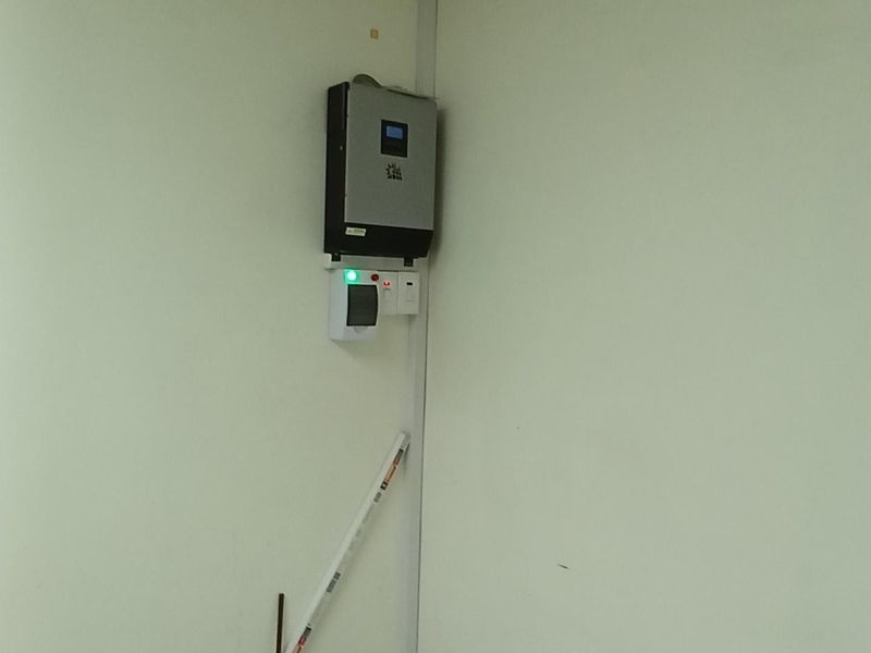 Utility space featuring a wall-mounted solar inverter and electrical distribution board with tiled flooring and suspended ceiling.