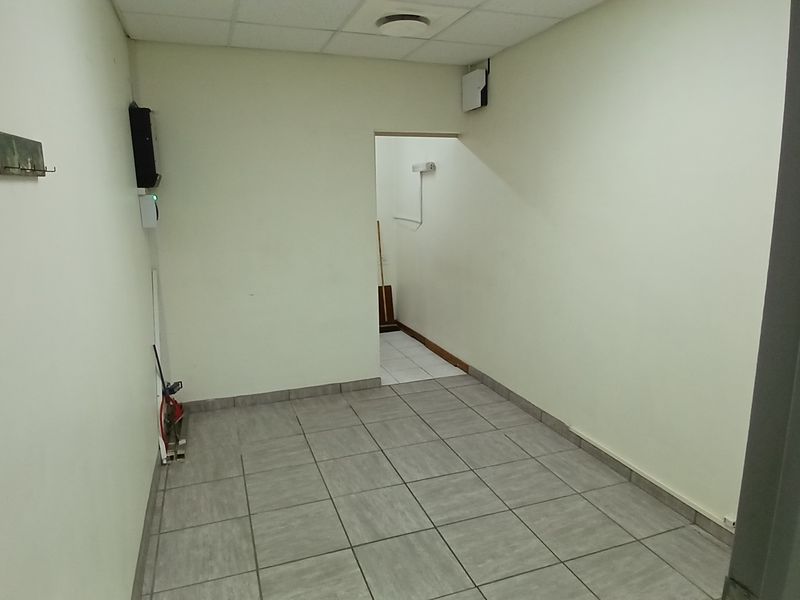 A functional, empty utility space featuring tiled flooring and a suspended ceiling, suitable for storage or administrative use.