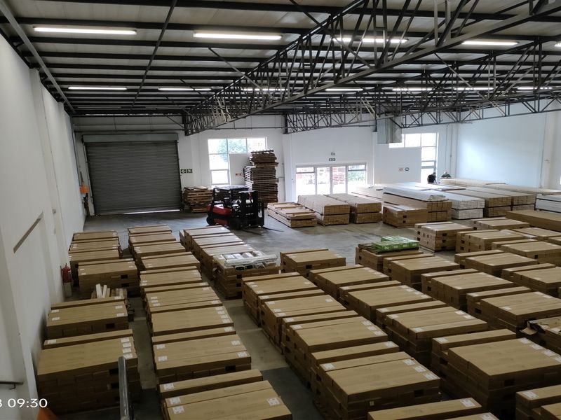 Spacious industrial warehouse featuring high ceilings with exposed steel trusses, concrete flooring, and a large roller shutter door for efficient loading access.
