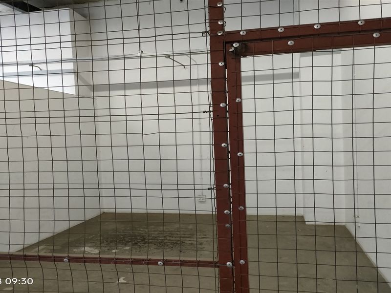 A secure, enclosed utility or storage area featuring concrete flooring and a heavy-duty wire mesh partition.