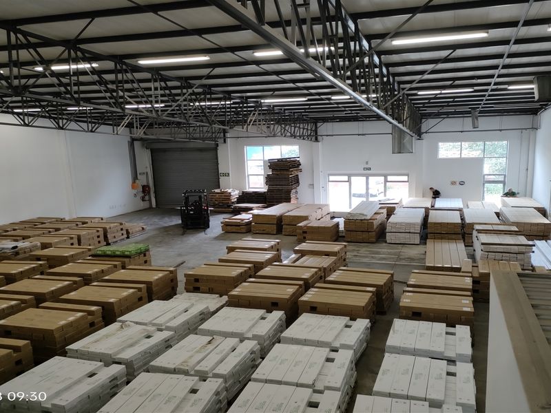 Spacious industrial warehouse featuring high ceilings with exposed steel trusses, concrete flooring, and a large roller shutter door for efficient loading access.