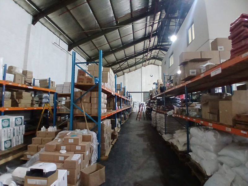 Industrial warehouse space featuring high-bay ceilings, exposed steel trusses, and extensive heavy-duty steel racking systems for storage.