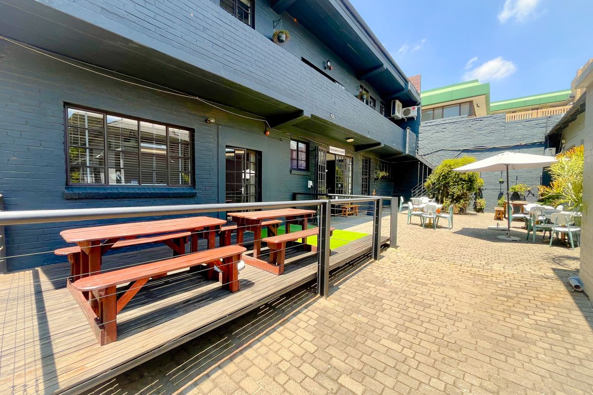 A paved outdoor courtyard area featuring a raised wooden deck, brick building facade, and exterior access points for office use.