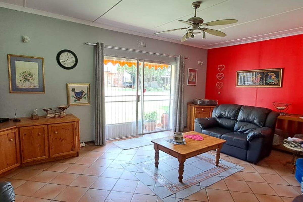 A spacious living room featuring tiled flooring, a ceiling fan, and a sliding glass door providing access to the outdoor area.