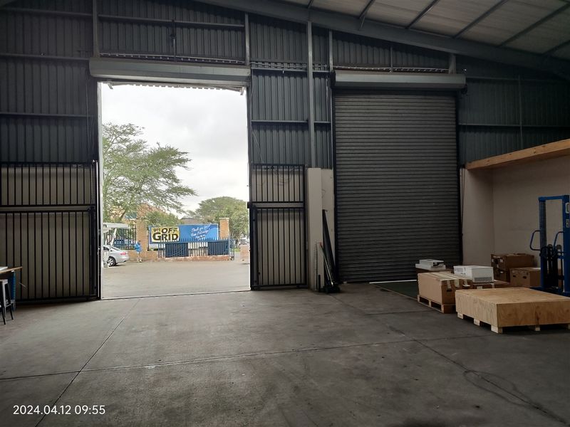 Spacious industrial warehouse unit featuring high ceilings, concrete flooring, and large roller shutter doors for easy vehicle and equipment access.