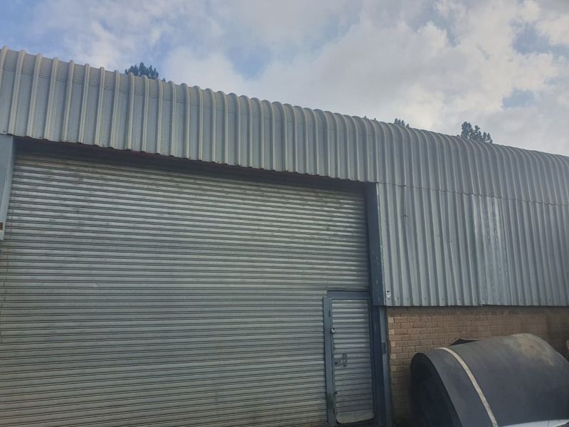 Industrial exterior facade featuring corrugated metal cladding, a large roller shutter door, and a secure pedestrian access door.