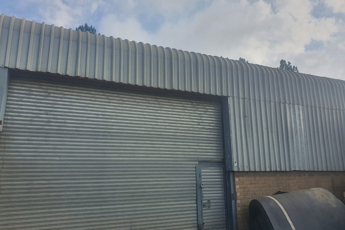 Industrial exterior facade featuring corrugated metal cladding, a large roller shutter door, and a secure pedestrian access door.