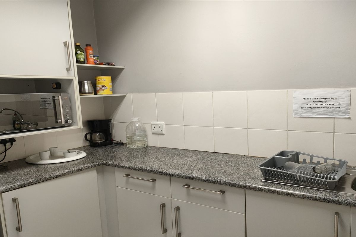 A functional kitchen area featuring white cabinetry, granite countertops, a tiled backsplash, and a built-in microwave.