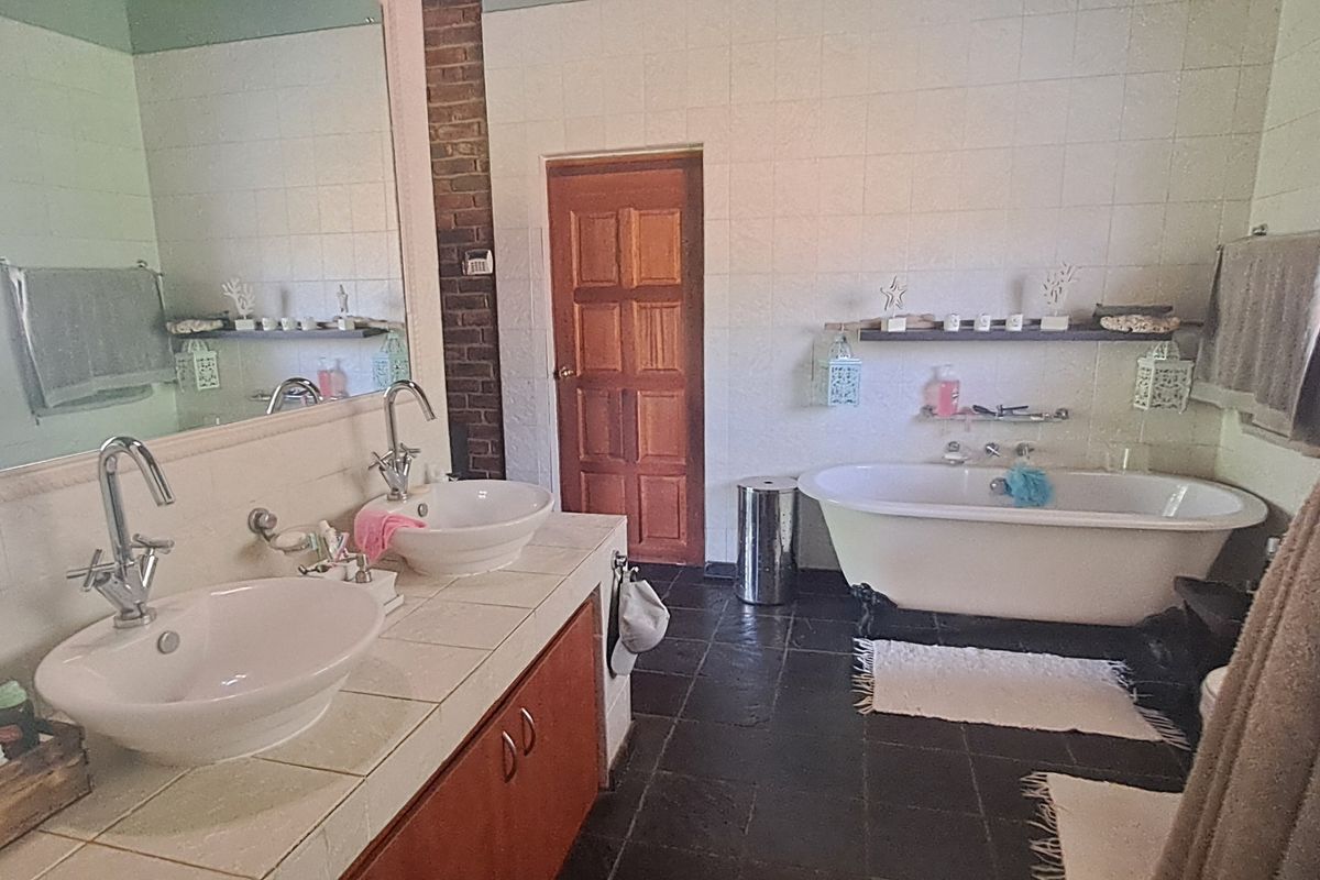 Spacious bathroom featuring a double vanity with tiled countertop, a classic freestanding bathtub, and tiled finishes throughout.