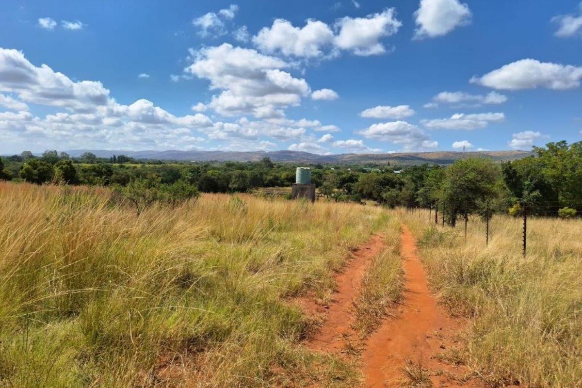 Expansive rural landscape view featuring a dirt access track, natural grassland, and a functional water storage tank on the property.