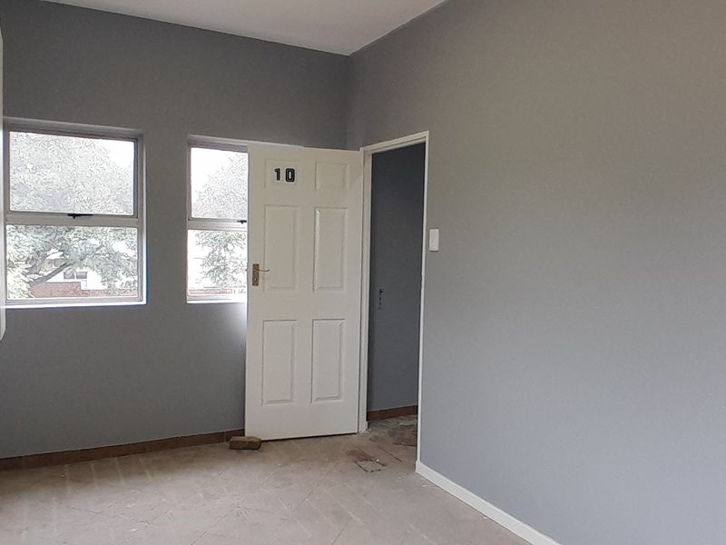 A vacant office space featuring grey walls, built-in cabinetry, and natural light from casement windows.
