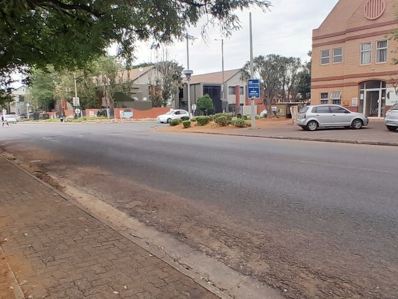 Street view showing the approach to the office building with paved sidewalk and asphalt road access.