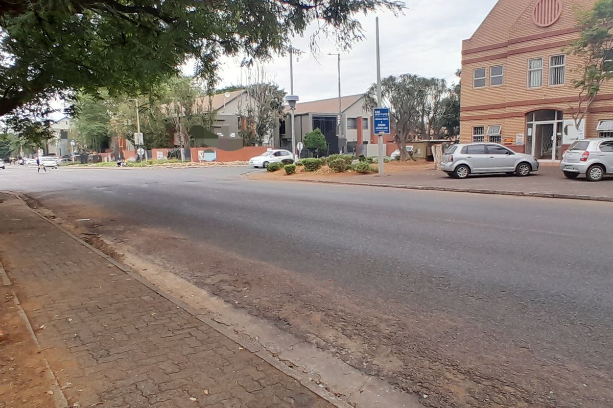 Street view showing the approach to the office building with paved sidewalk and asphalt road access.
