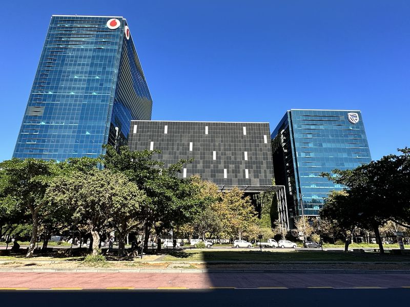 A professional exterior view of a modern multi-story office complex featuring glass curtain wall facades and landscaped surroundings.