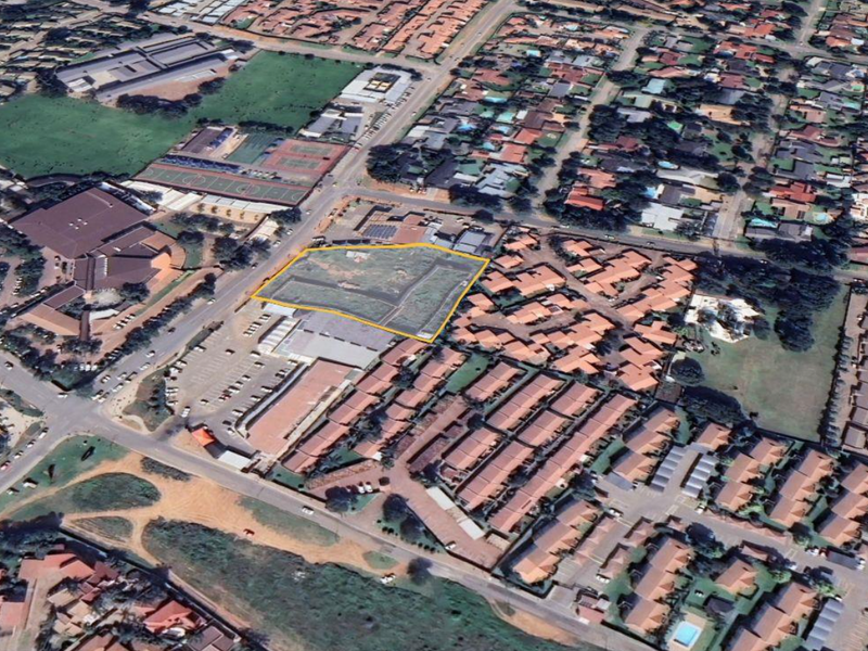 An aerial view highlighting a vacant land parcel situated within a developed commercial and residential area, showing surrounding road access and nearby infrastructure.