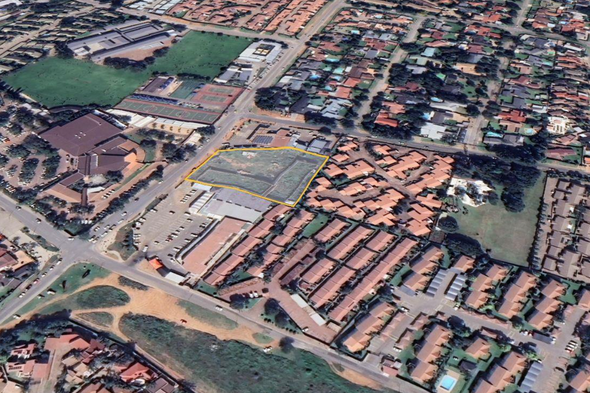 An aerial view highlighting a vacant land parcel situated within a developed commercial and residential area, showing surrounding road access and nearby infrastructure.