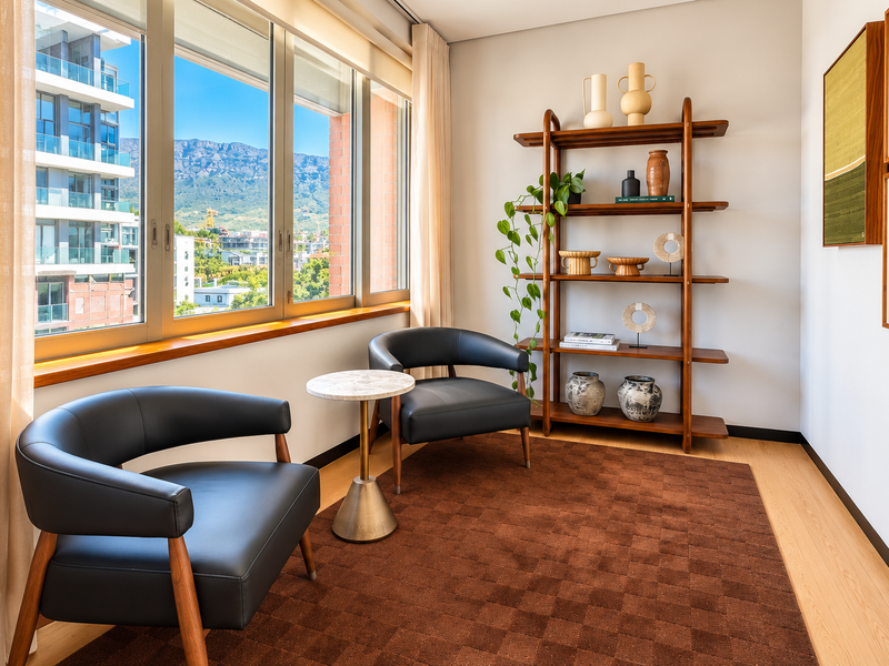 A bright, modern office space featuring large windows with mountain views, light wood flooring, and clean, neutral wall finishes.