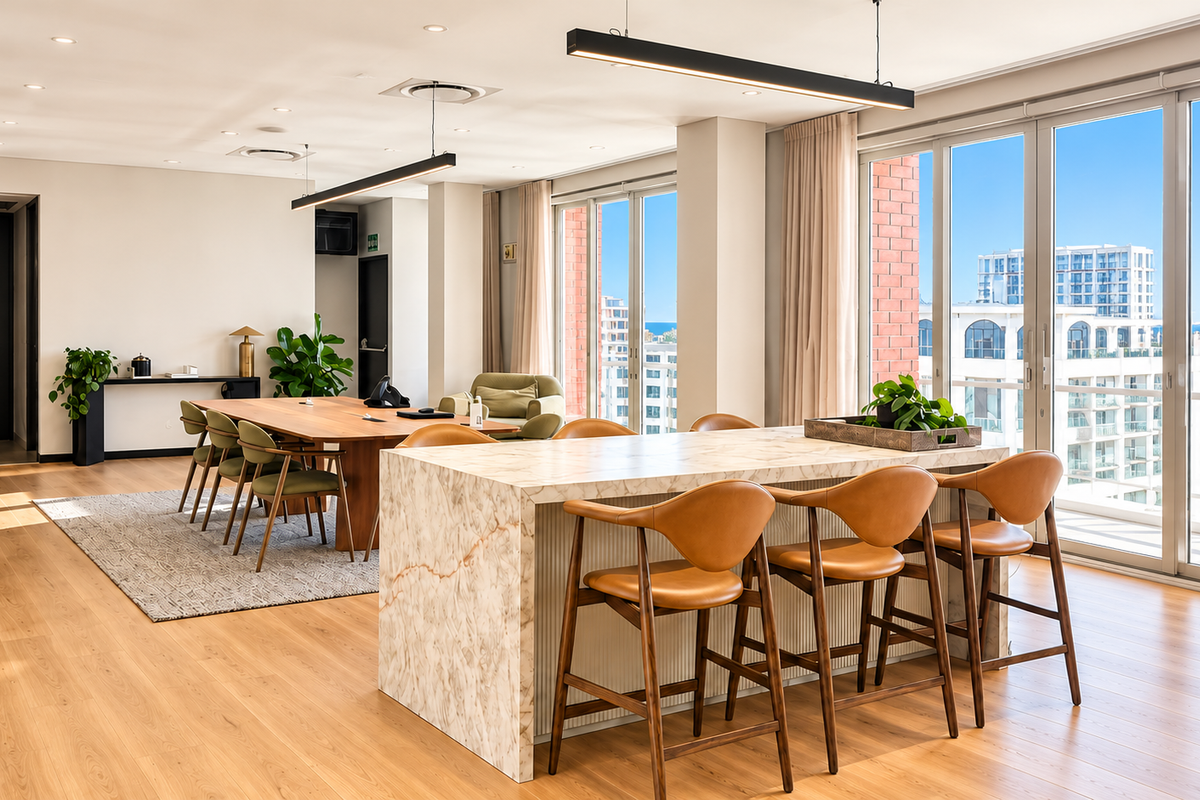 Modern, high-end office space featuring a marble-topped island, hardwood flooring, and expansive floor-to-ceiling windows with natural light and city views.