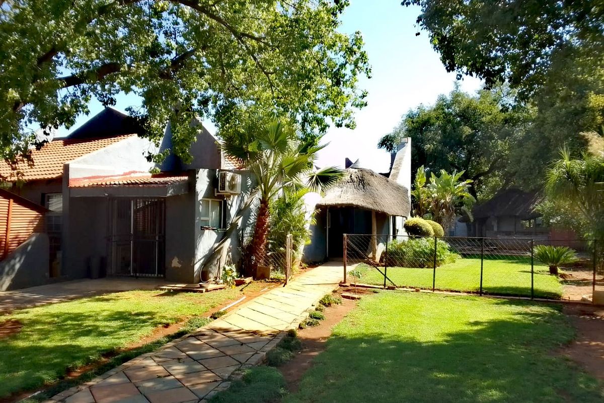 Rear view of the farm property featuring a mix of thatched and tiled roofing, a paved garden path, and established lawn area.