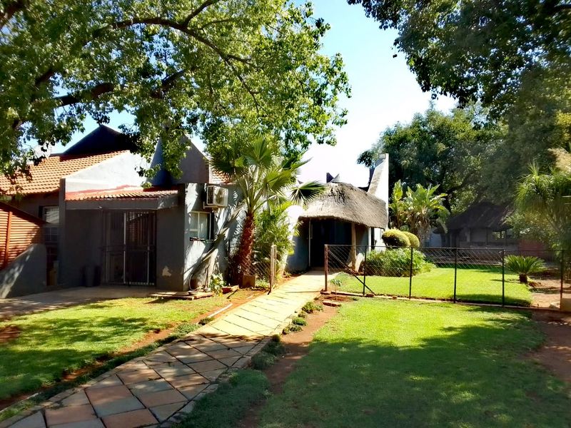 Rear view of the farm property featuring a mix of thatched and tiled roofing, a paved garden path, and established lawn area.