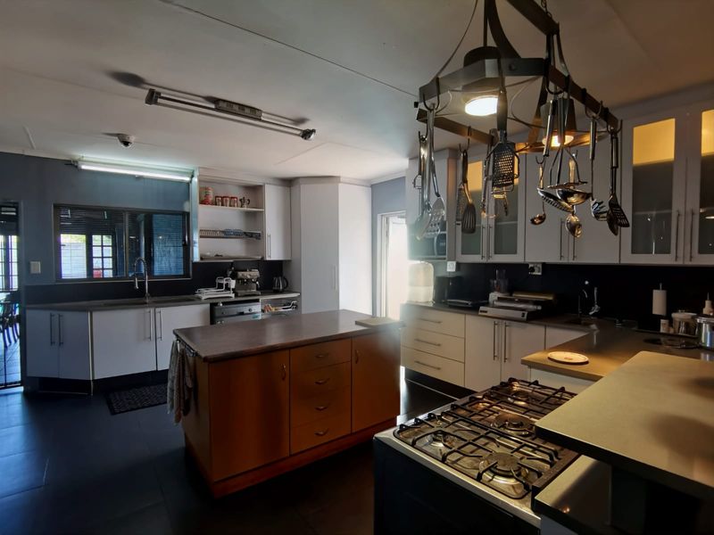Spacious kitchen featuring a central island, gas hob, ample built-in cabinetry, and a functional layout with a dedicated sink area.