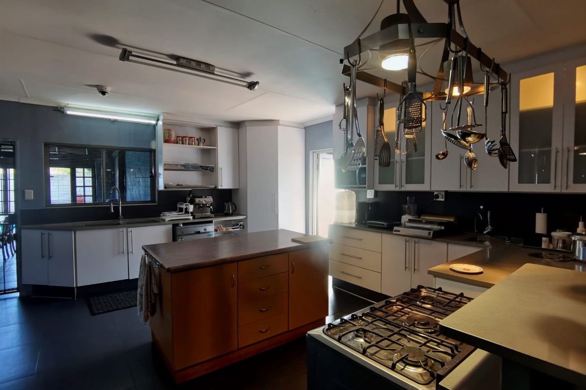 Spacious kitchen featuring a central island, gas hob, ample built-in cabinetry, and a functional layout with a dedicated sink area.