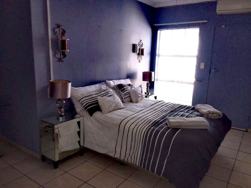 A bedroom featuring tiled flooring, an integrated air conditioning unit, and natural light from a window.