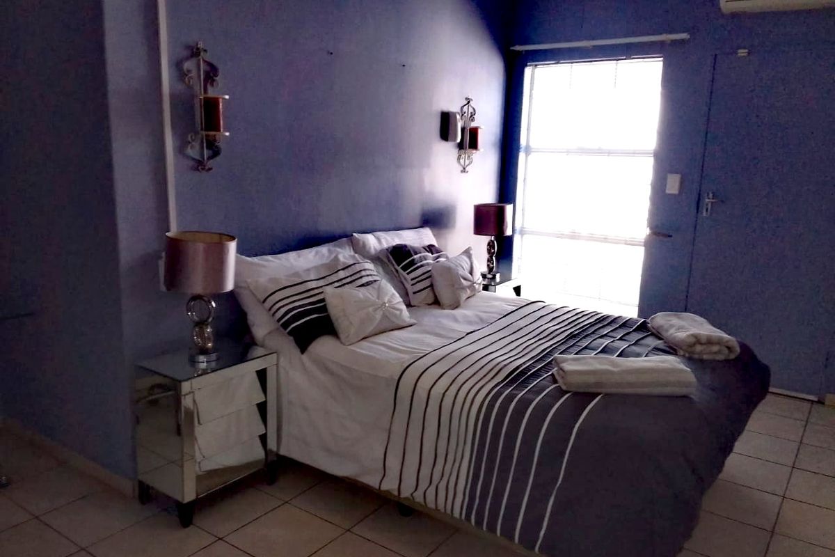 A bedroom featuring tiled flooring, an integrated air conditioning unit, and natural light from a window.