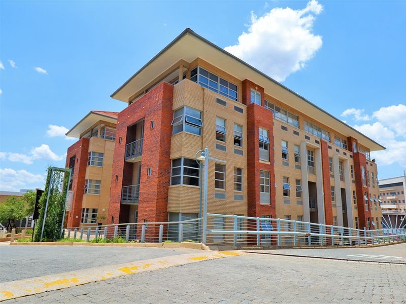 A multi-story office building featuring a modern brick facade, large casement windows, and a paved entrance area.