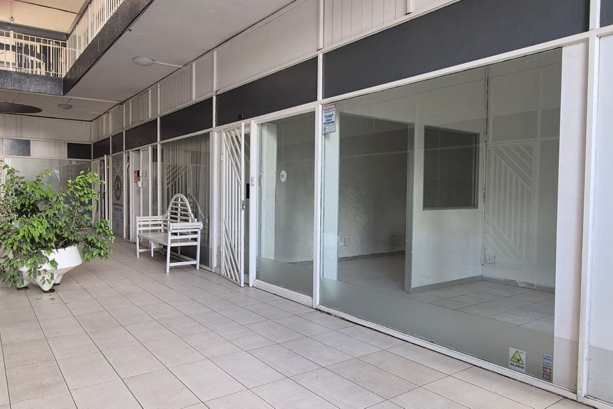 A vacant office space featuring a large glass storefront, tiled flooring, and secure access, suitable for a professional workspace or retail unit.