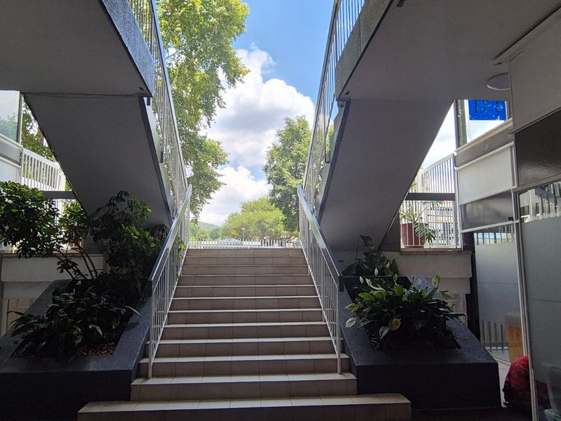 An outdoor staircase leading to an upper level, featuring tiled steps, metal railings, and integrated planters.