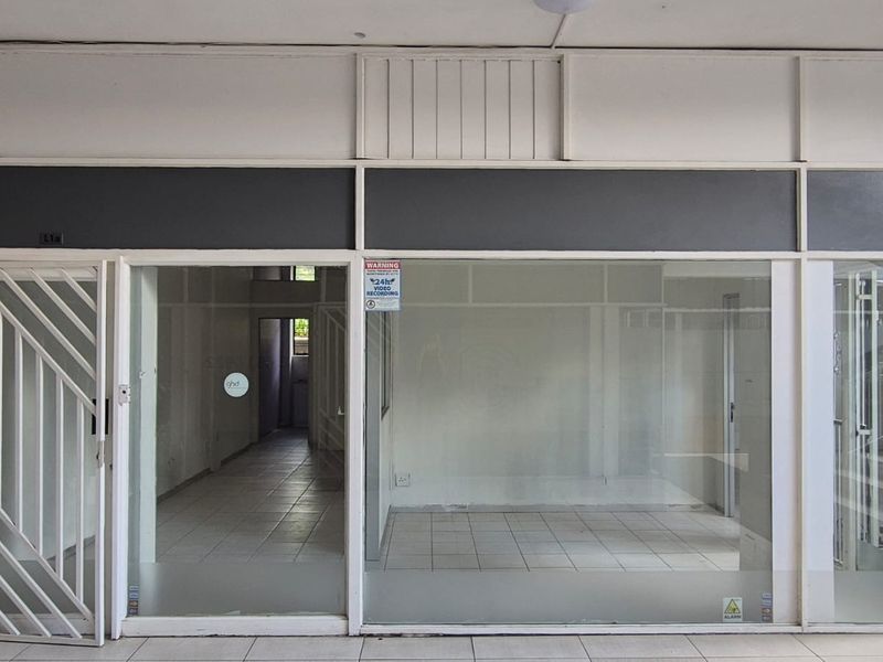 Vacant office space featuring a glass storefront, security gate, and tiled flooring, suitable for retail or professional use.