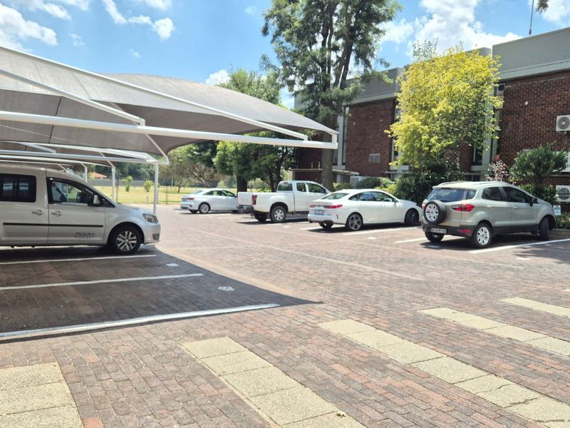 Office property exterior featuring a paved parking area with shade cloth carports and brick building facade.