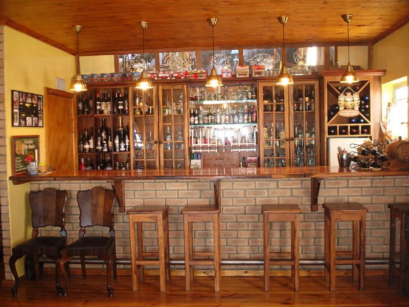 A rustic-style built-in bar area featuring a brick base, timber ceiling, and extensive glass-fronted cabinetry for display and storage.